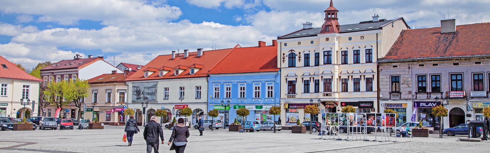 Widok na rynek w Oświęcimiu z zabytkowymi kamienicami wokół.