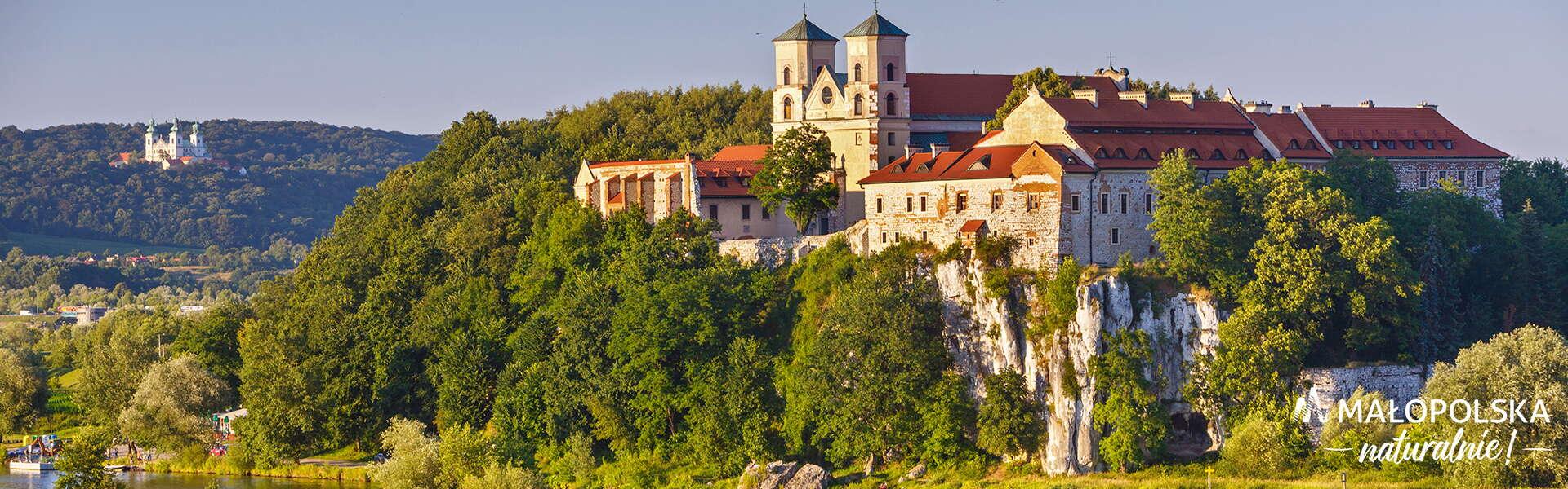 Opactwo Benedyktynów w Tyńcu nad Wisłą na wysokiem skale. Na zdjęciu nałożone logo: napis Małopolska naturalnie.